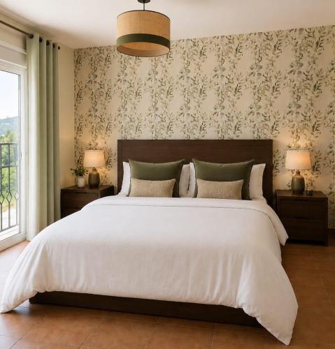 a bedroom with a large white bed with a wall at Marbella Views in Ojén