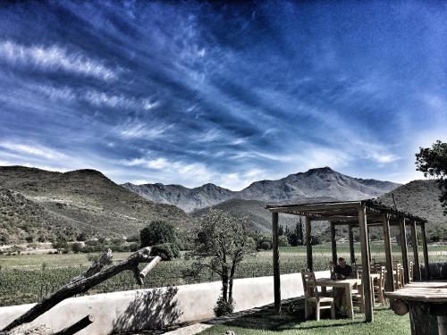 a person sitting at a table with a view of mountains at De Kombuys in Oudtshoorn