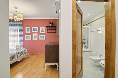 a bathroom with a red wall and a sink and a toilet at Brisa Do Mar Moura Beach in Quarteira