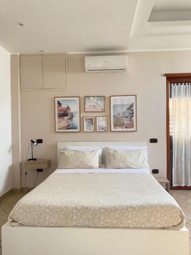 a white bedroom with a large bed and pictures on the wall at Carla's studio in Pompei