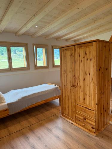 ein Schlafzimmer mit einem Bett und einem großen Holzschrank in der Unterkunft Hotel Grimsel in Obergesteln