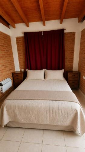 a bedroom with a large bed with a red curtain at Cabañas Pá Que te Vengas in Trapiche