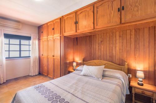 a bedroom with a bed with wooden walls and cabinets at Apartamento B Armonia Rural in Granadilla de Abona