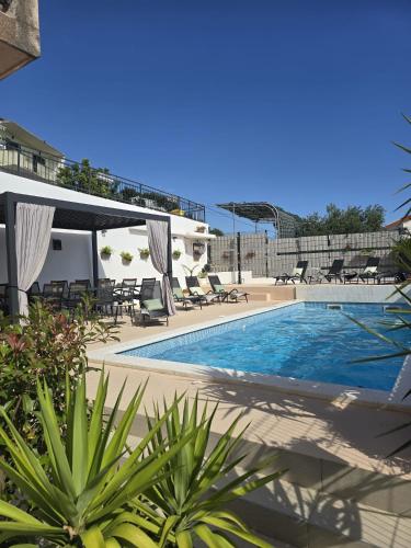 a swimming pool with chaise lounge chairs next to a building at Villa Joy- Paradise near Split by Istra Vacation in Kučine