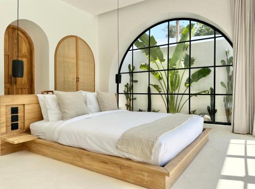 a bedroom with a large bed and a large window at Melrose x The Young Villas in Uluwatu