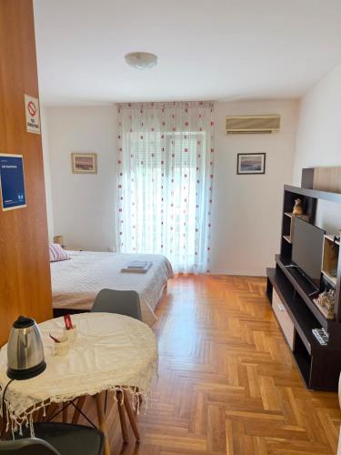 a bedroom with a bed and a table and a tv at Laki Apartment in Podgorica