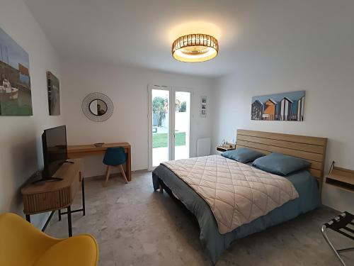 a bedroom with a bed and a desk and a computer at La Barjuline - Île d'Oléron in La Brée-les-Bains