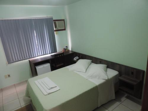 a small bedroom with two beds and a window at Hotel Demarchi in Rio do Sul