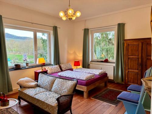 a living room with a bed and a couch and windows at Bellevue - mit Balkon und Aussicht in Maring-Noviand