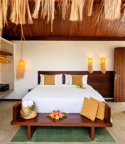 a bedroom with a large white bed and a bench at Kuarasy Pousada de Charme Japaratinga in Japaratinga