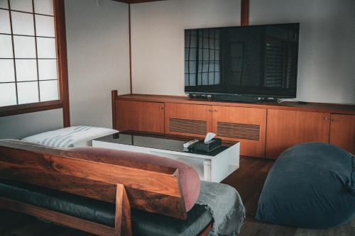 a room with a tv and a couch and a chair at ウエダハウス in Ueda