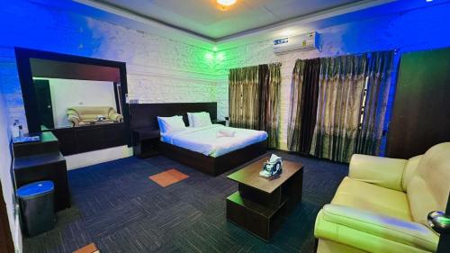 a bedroom with a bed and a couch and a mirror at Hotel Marvellen Inn Ltd in Dhaka