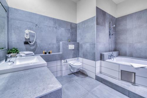 a bathroom with a tub and a toilet and a sink at Hotel Continental in Pilsen