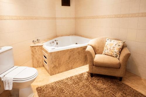 a bathroom with a tub and a chair and a toilet at Guarita Park Hotel - By Life Hotéis in Torres