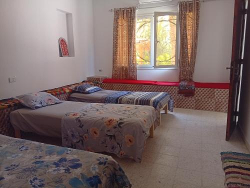 a room with three beds and a window at La tente tamaghza in Tamaghzah