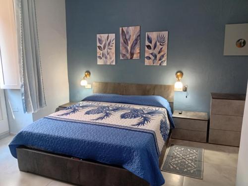 a bedroom with a blue bed with three paintings on the wall at Astrolicamus, Intero Alloggio con camera e bagno in Bosa