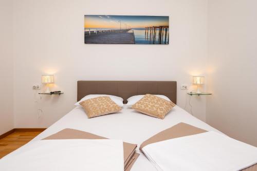 a bed with two pillows and a picture on the wall at Kathy House in Slatine