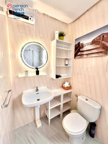 a bathroom with a sink and a toilet and a clock at Pensión RENCH in Alcossebre