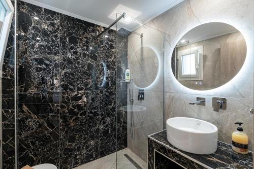 a bathroom with a sink and a shower with a mirror at EriZen Jacuzzi suites in Keramoti