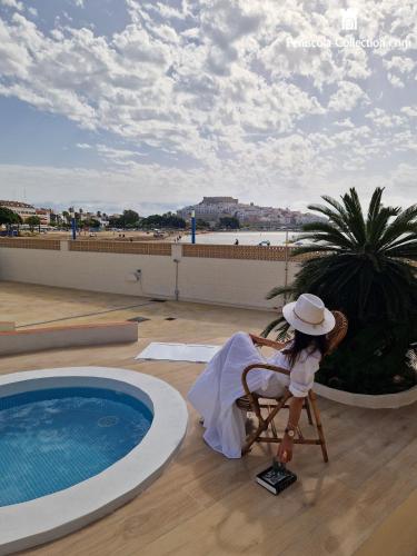 a woman sitting in a chair next to a swimming pool at Villa Brisamar - On the beach in Peniscola