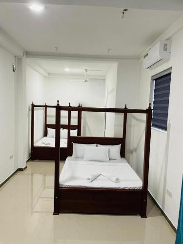 a bedroom with two bunk beds with white sheets at Kalupahana Villa in Beruwala