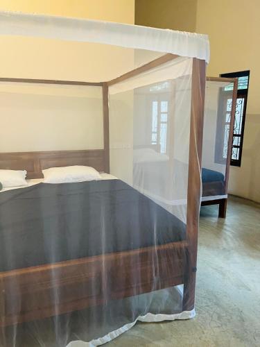 a bedroom with a canopy bed and a chair at Hakkeem's Homestay in Arugam Bay