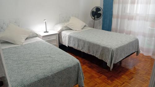 a bedroom with two beds and a table with a lamp at A parada da Ribeira in Ourense