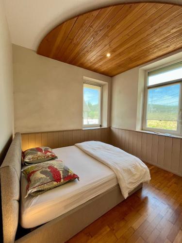 a large bed in a room with two windows at Appartement 93m2 Cosy - 2 chambres in Wimmenau
