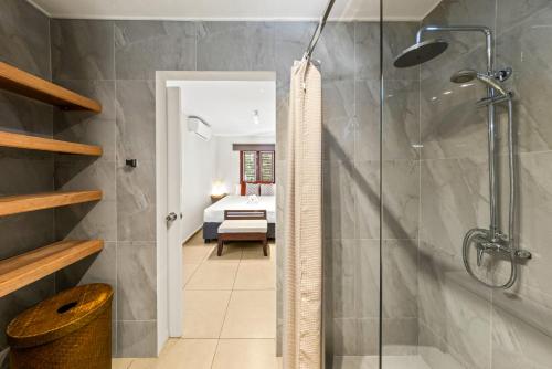 a bathroom with a shower and a bedroom at Atlantis Beach House in Willemstad