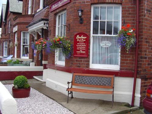 a bench in front of a building with flowers at Boulmer Guest House in Whitby