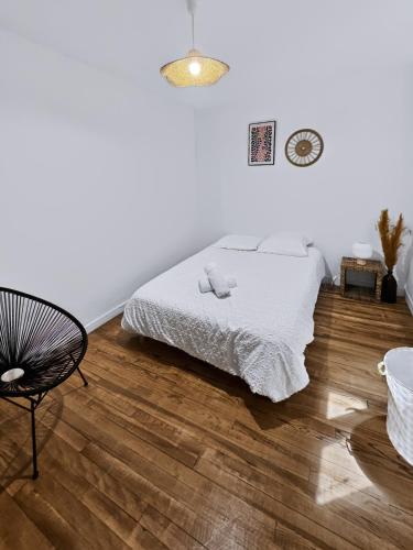 a white bedroom with a bed and a chair at Le Citadin - Centre - Wifi - Balcon in Dax