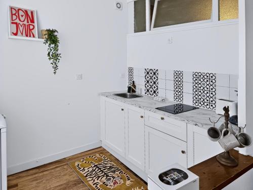a white kitchen with a sink and a counter at Le Citadin - Centre - Wifi - Balcon in Dax