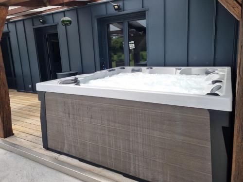 a bath tub sitting on a deck in a house at Le Rameau Gîte avec spa et étangs privés in Langey