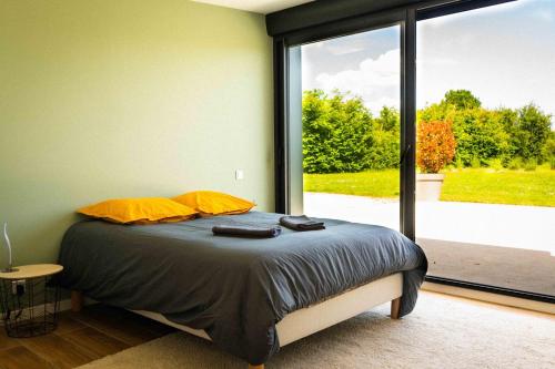 a bedroom with a bed and a large window at Le Rameau Gîte avec spa et étangs privés in Langey