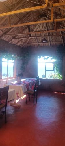 a room with two tables and chairs and windows at TAQUILE LODGE Perú in Huillanopampa