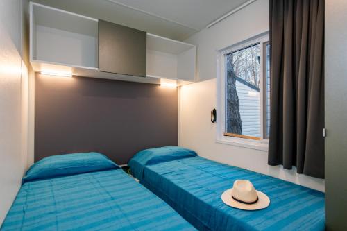 two beds in a room with a hat on it at Camping Iscrixedda in Lotzorai
