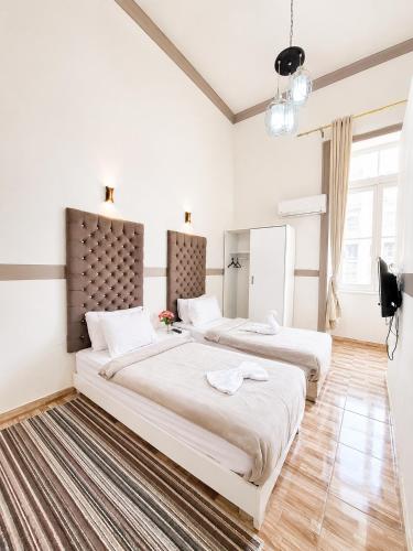 two beds in a bedroom with white walls and wood floors at Velvet city view in Cairo