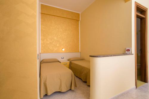 ランペドゥーザにあるBed & Breakfast Isola Bella Lampedusaのベッド2台、冷蔵庫が備わる小さな客室です。
