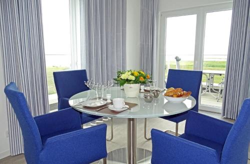 a dining room with a glass table and blue chairs at Sturmvogel in Olpenitz