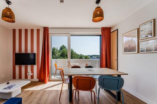 a dining room with a table and chairs and a large window at Apartment for 5 with a forest view in La Teste-de-Buch