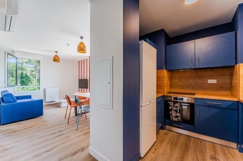 a kitchen with blue cabinets and a living room with a table at Apartment for 5 with a forest view in La Teste-de-Buch