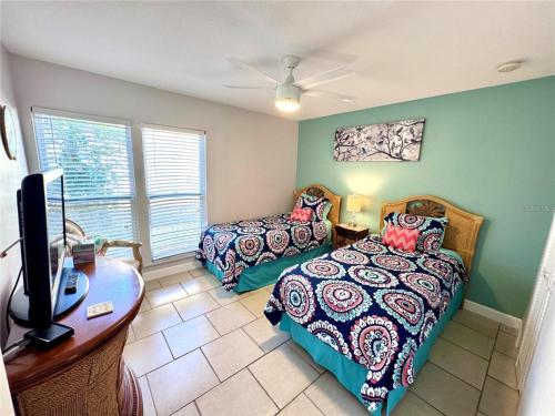 a bedroom with two beds and a desk and a tv at 2BR/2BA condo Sienna Park in Sarasota