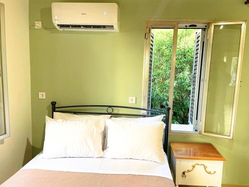 a bedroom with a bed and a window with a fan at Chalikas Vintage Cottage in Mytilene