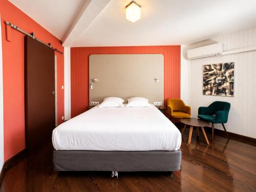 una camera da letto con un grande letto e due sedie di Hotel Thonon Centre Le Comte Rouge a Thonon-les-Bains