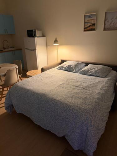 a bedroom with a bed and a table and a kitchen at Studio des dunes au clocher in Berck-sur-Mer