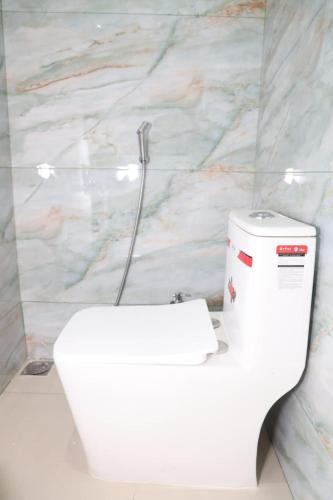 a white toilet in a bathroom with a marble wall at Muthu Seaview Residency in Kuilapayam