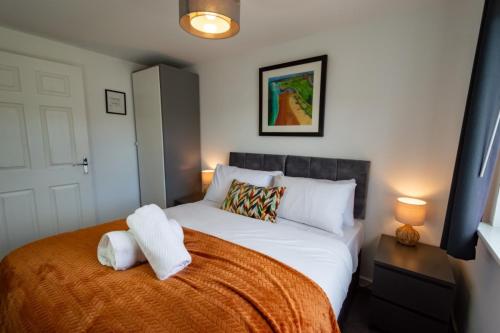 a bedroom with a large bed with an orange blanket at Spacious 5BR Home St Andrews in Fife