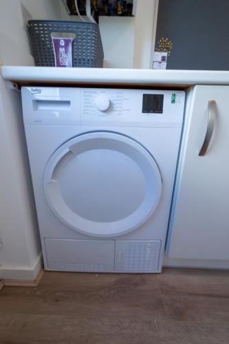 a white washer and dryer sitting under a counter at Spacious 5BR Home St Andrews in Fife