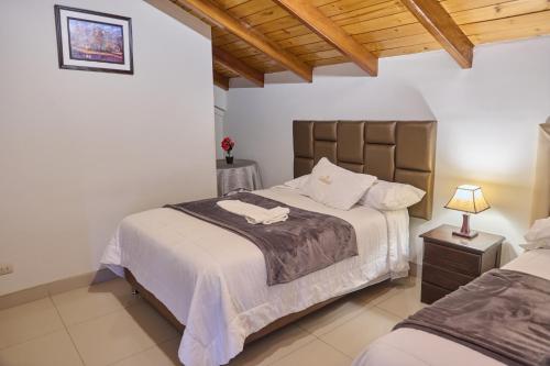 a bedroom with two beds and a wooden ceiling at Hostal Catequil in Cajamarca