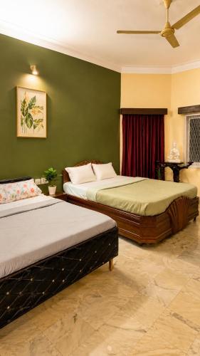 two beds in a room with green walls at Clean Culture Retreat in Mysore